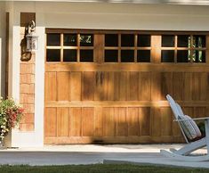 a white lawn chair sitting in front of a garage door with flowers on the side