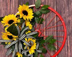 sunflowers and greenery tied to a bicycle wheel on a wooden table top