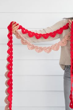 a woman holding up a red crocheted scarf