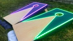 two illuminated cornhole boards sitting in the grass