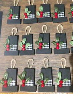 small black boxes with red berries and green leaves are arranged on a wooden table top