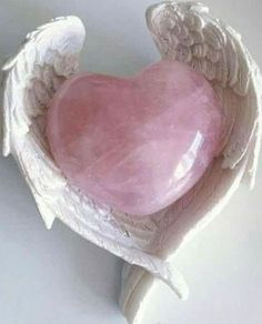 an angel's wing holding a pink heart