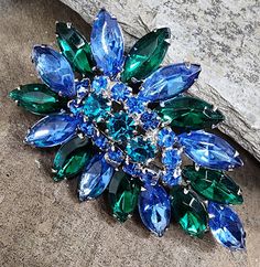 Vintage estate costume jewelry brooch in the shape of a leaf with an outer ring of large blue and green navette rhinestones circling an inner ring of circular cut stones, all prong set in a silver setting. The pin has a style reminiscent of Juliana. Maker: Unknown Signed: No Size: 2 5/8 inches long. Condition: Excellent condition with no damage and only some very faint surface wear to the back as pictured. Refer to the photos for a better idea of the condition, you will receive the exact piece of estate jewelry that is pictured. Other: - Stylized Leaf, Jewelry Brooch, Leaf Jewelry, Blue And Green, Estate Jewelry, Prong Setting, Costume Jewelry, Antique Jewelry, Brooch Pin