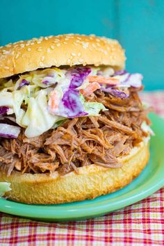 a pulled pork sandwich with cole slaw on a green plate