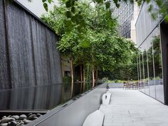 an empty walkway in front of a building with trees on both sides and benches to the side