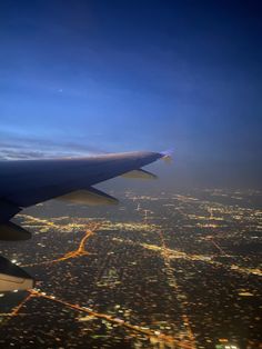 an airplane wing flying over the city lights