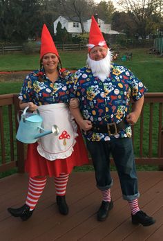 two people dressed as gnomes standing on a deck with an apron and watering can