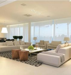 a living room filled with lots of furniture and large windows overlooking the cityscape