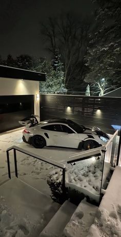 two sports cars parked in the snow at night with their lights on and behind them