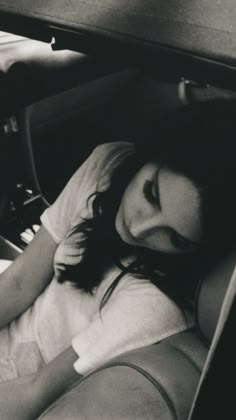 a woman laying in the back seat of a car with her head resting on a pillow