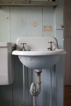 a white sink sitting next to a toilet on top of a wooden floor in a bathroom