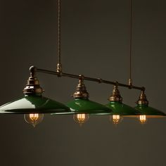 three green lights hanging from a ceiling fixture in a dark room with no one around them