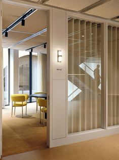 an office with glass walls and yellow chairs