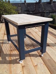 a kitchen island sitting on top of a wooden floor next to a building with a sky background