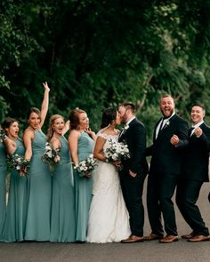 a group of people standing next to each other in front of some trees and bushes