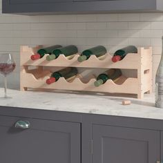 a wine rack with bottles and glasses on a counter top next to cabinets in a kitchen