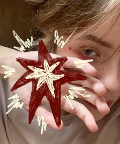 a woman holding up a red and white star in front of her face with words written all over it