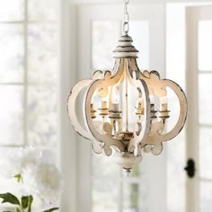 a chandelier hanging from the ceiling in a room with white walls and windows