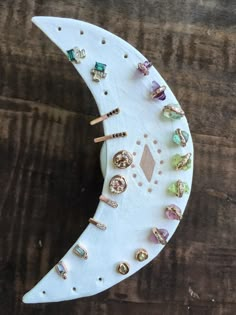 a white moon with lots of different colored jewels on it's side and some gold rings hanging from the top