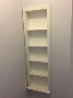 an empty white shelf in the corner of a room