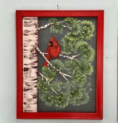 a red bird sitting on top of a tree branch next to a forest filled with green leaves