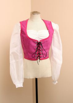 a mannequin wearing a pink and white blouse with laces on the front