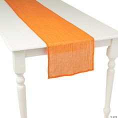 an orange and white table runner is on top of a white table with two legs