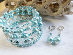 two bracelets and earrings are sitting on a table next to some sea glass beads