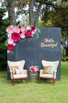 two chairs sitting in front of a large sign with flowers on it's side