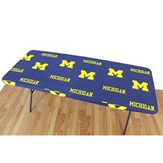 a blue and yellow table cover with michigan letters on the top, sitting on a wooden floor