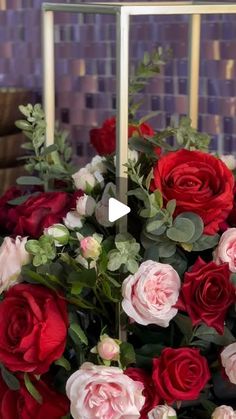 a vase filled with lots of red and pink flowers sitting on top of a table