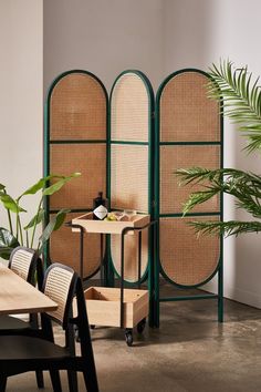 the room dividers are made out of bamboo and green caned screens, with two chairs