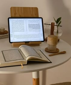 an open book sitting on top of a table next to a computer monitor and keyboard