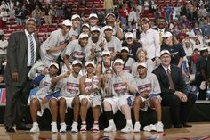 the men's basketball team is posing for a photo on the court with their trophy