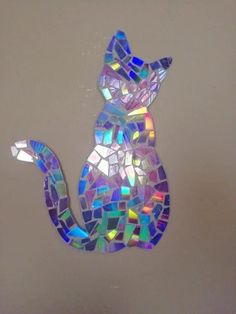 a cat made out of small pieces of glass mosaics on a white wall in the shape of a cat