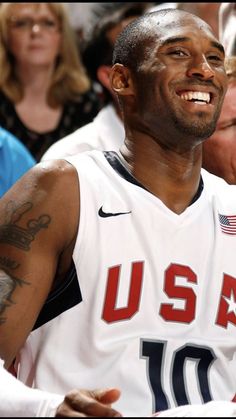 a man with tattoos on his arm sitting in front of a group of people and smiling