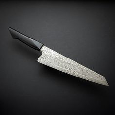 a knife that is sitting on top of a table next to a black surface with writing on it