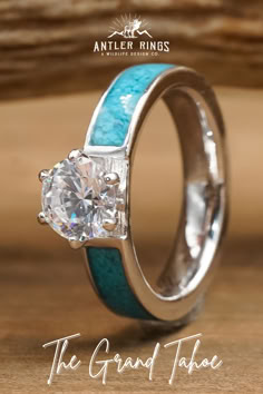 an engagement ring with turquoise and white enamel inlays on the sides, set against a wooden background