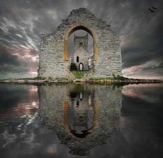 an old stone building sitting on top of a body of water under a cloudy sky