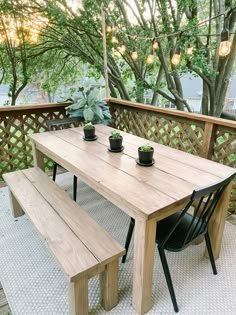 a wooden table sitting on top of a patio next to a bench and potted plants