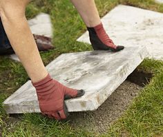 a person wearing red gloves and socks on top of a stone slab in the grass