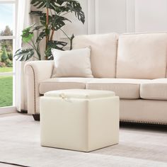 a living room with a couch, chair and footstool in front of a window