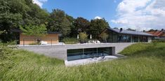 a modern house in the middle of a grassy area with trees and grass around it