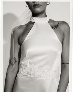 a woman in a white dress with tattoos on her arm and neck, wearing a veil