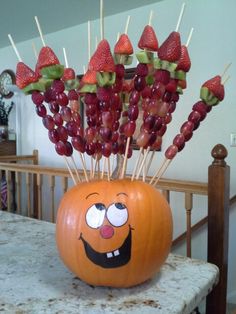 a pumpkin with strawberries and grapes in it