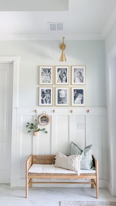 a white room with pictures on the wall and a wooden bench in front of it