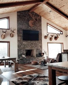 a living room filled with furniture and deer heads mounted to the wall above a fireplace