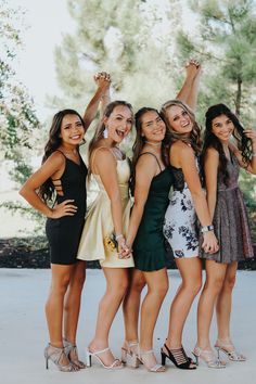 four young women posing for the camera with their arms in the air