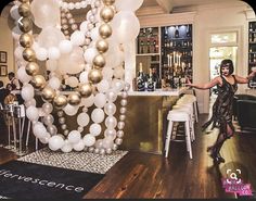 a woman standing in front of a bar filled with balloons