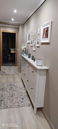 a long hallway with white furniture and pictures on the wall, along with an area rug